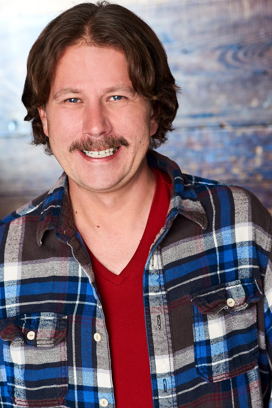 Joe Uhlarik headshot, grinning, plaid flannel shirt